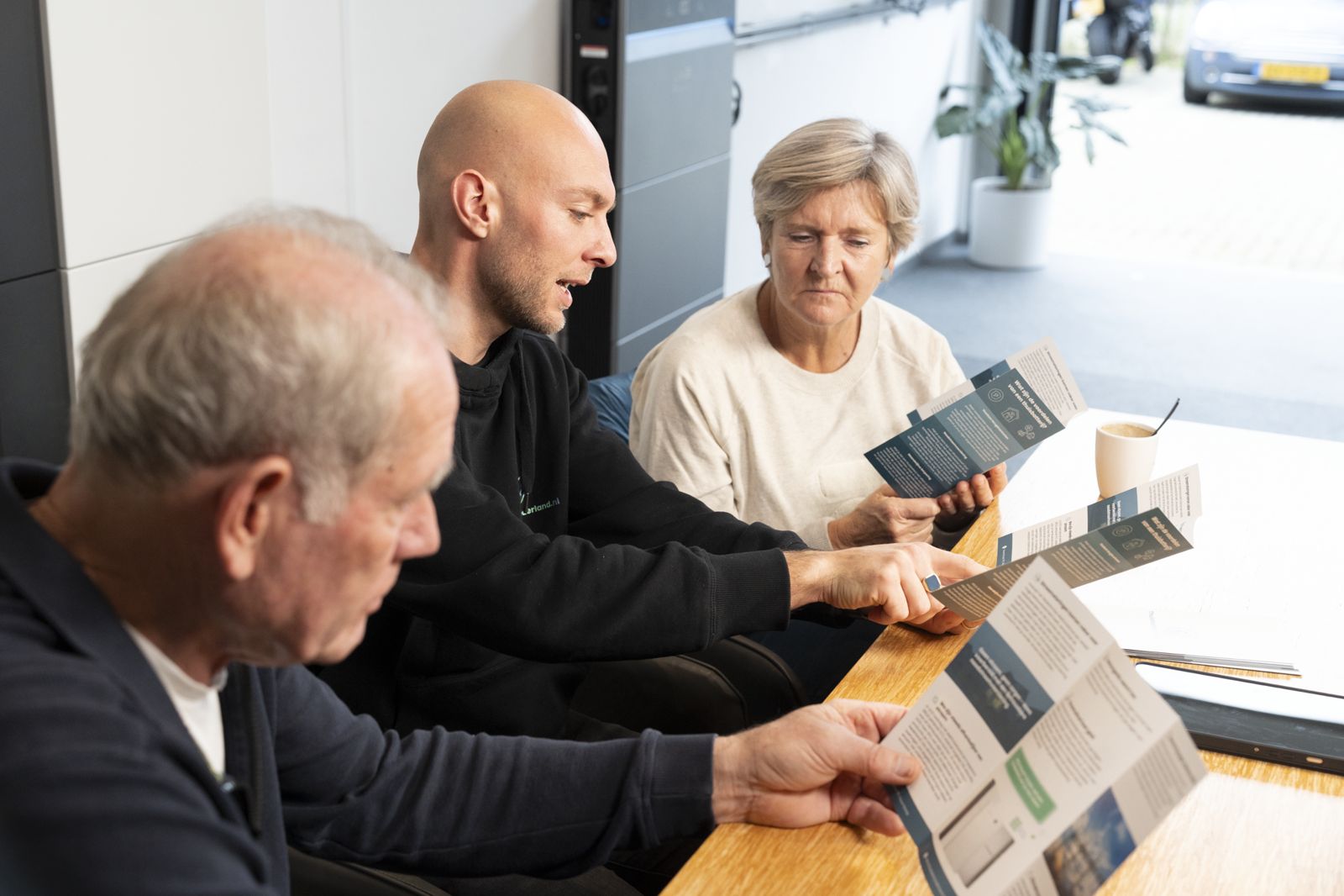 Adviseur neemt aan tafel het advies en de informatie over thuisbatterijen door met een echtpaar