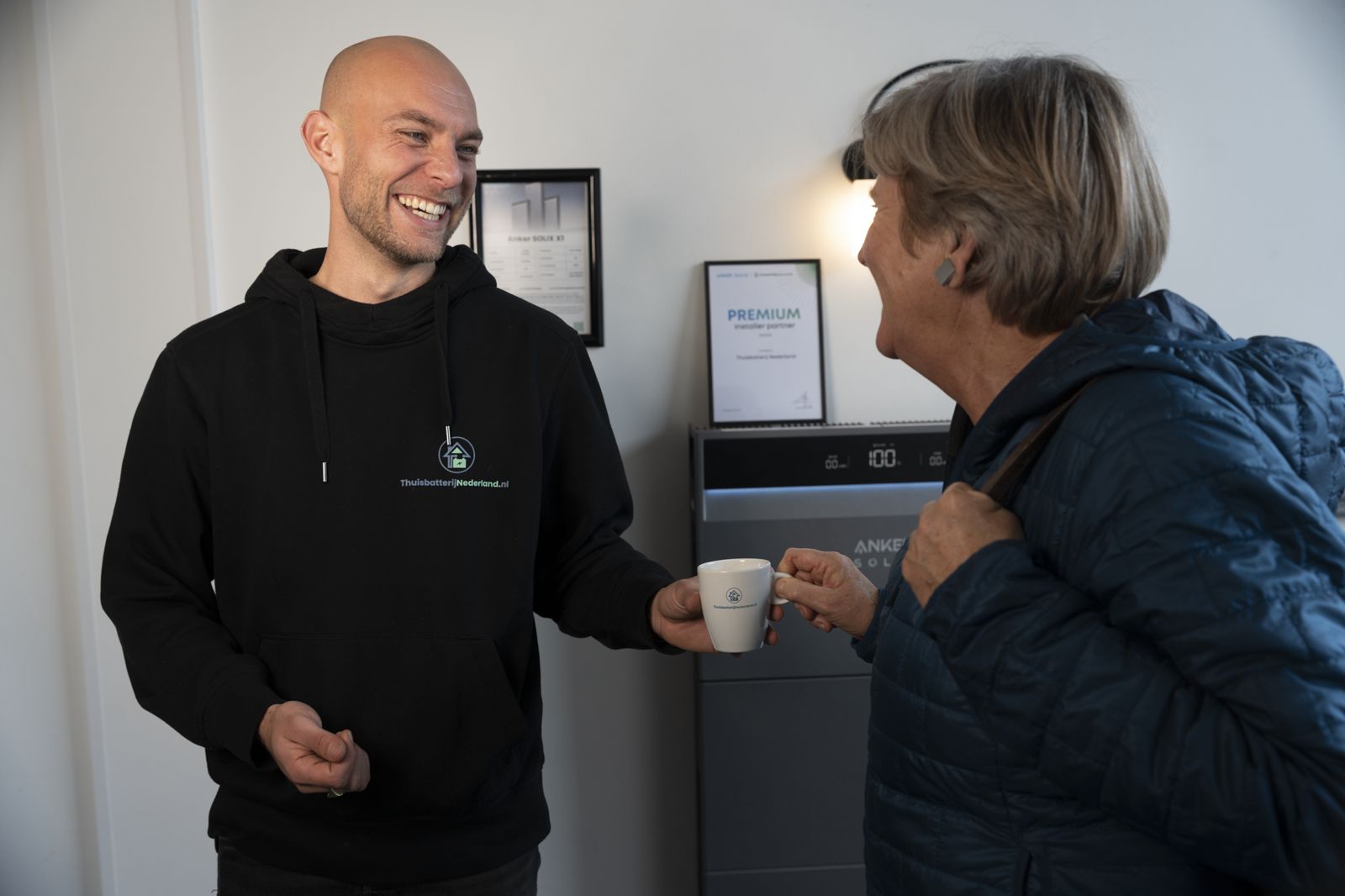 Bezoekster krijgt koffie bij binnenkomst in de thuisbatterij showroom in Nieuw-Vennep
