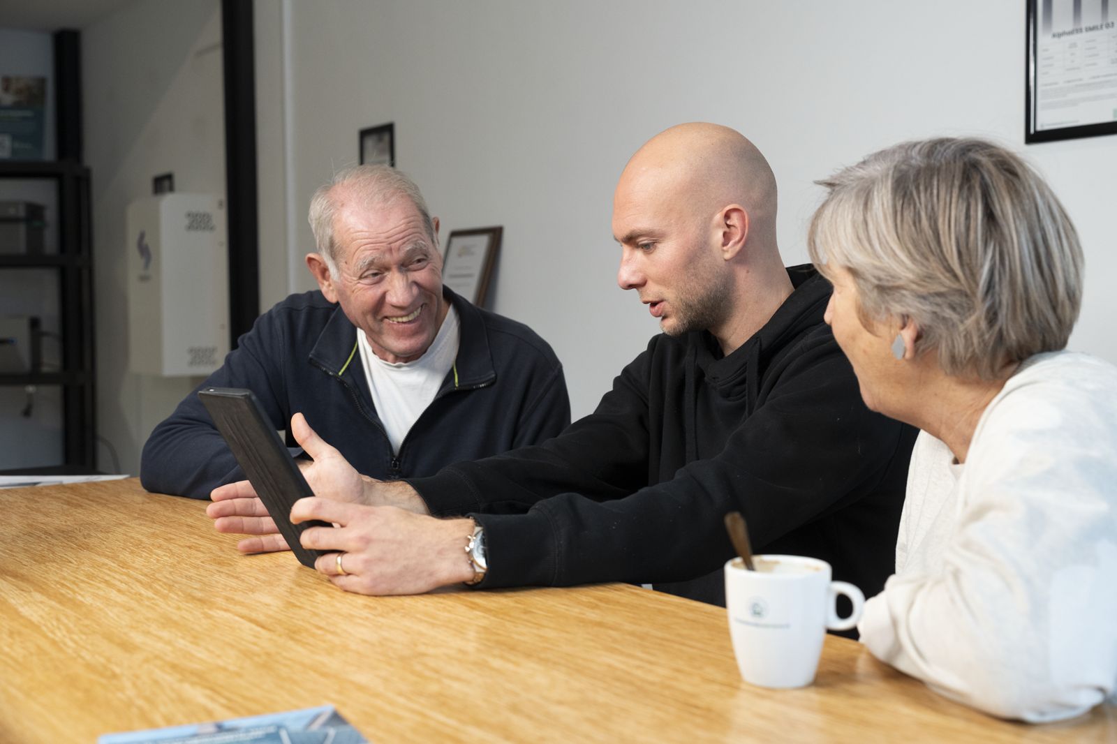 Adviseur bespreekt het advies op een tablet met een echtpaar tijdens een gratis thuisbatterij consult